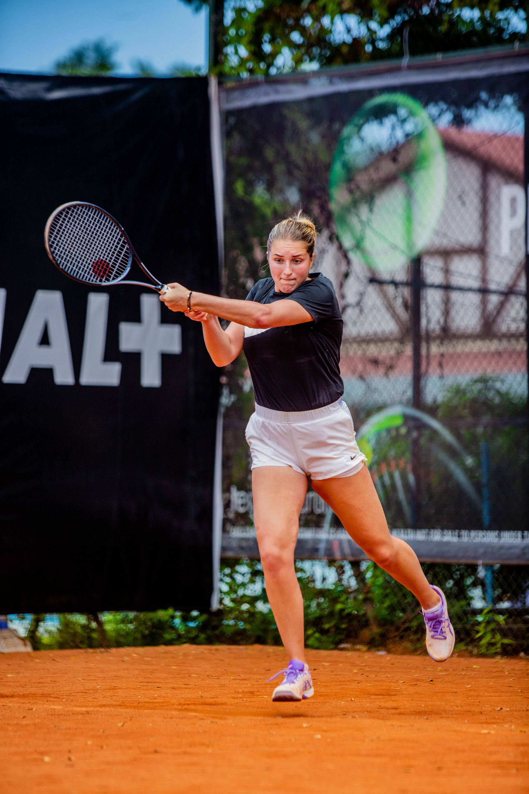 Adult player striking a two-handed backhand during a lesson