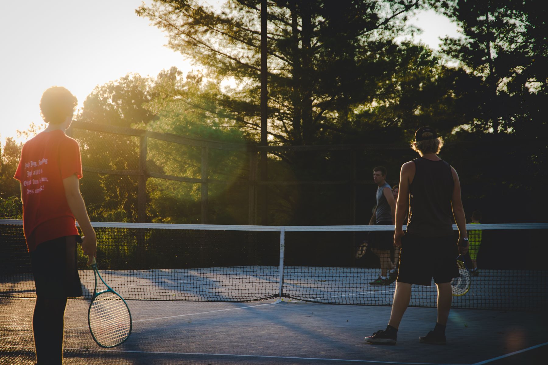 Two players rallying on an outdoor court during golden hour