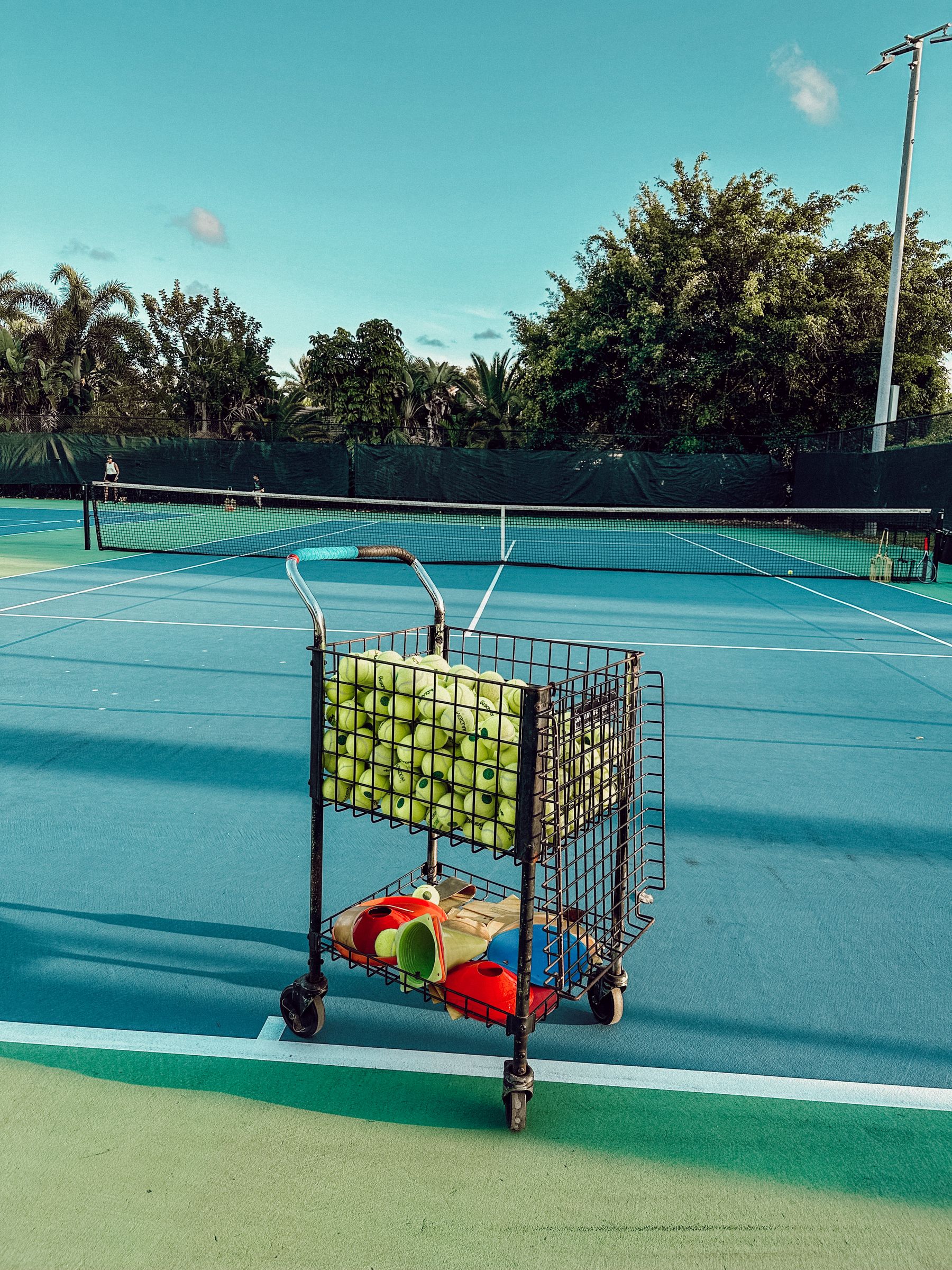Ball cart and racquets ready on a blue outdoor court